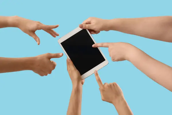 Women pointing at blank tablet computer on blue background