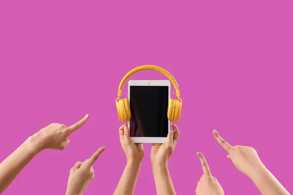 Women with blank tablet computer and headphones on purple background
