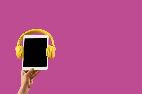 Woman with blank tablet computer and headphones on purple background