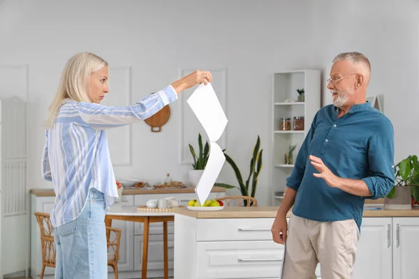 Mature couple with divorce decrees in kitchen
