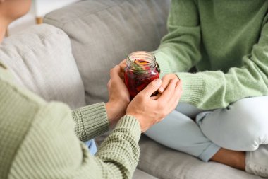 Oturma odasındaki kanepede oturmuş sıcak şarap içen bir çift.