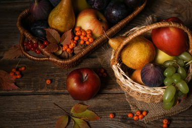 Tahta arka planda farklı taze meyveler olan sepetler.