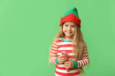 Yeşil arka planda şeker kamışları olan elf kostümlü şirin küçük kız.