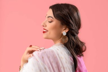 Pembe arka planda sarili güzel bir Hintli kadın.