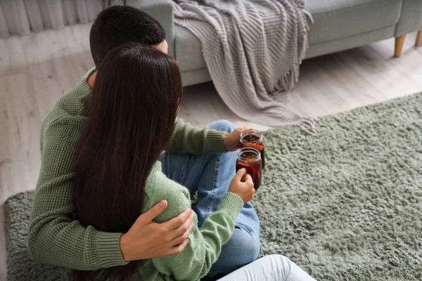 stock image Couple with glasses of warm mulled wine in sitting on floor living room