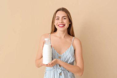 Bej arka planda sütü olan mutlu genç bir kadın.