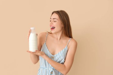 Bej arka planda sütü olan mutlu genç bir kadın.