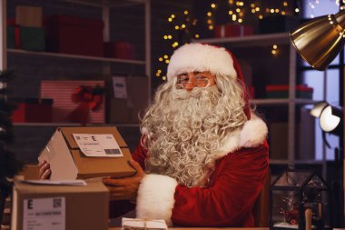 Postanedeki masada paketli Noel Baba oturuyor.