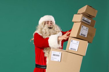 Yeşil arka planda yığınla düşen paketler olan Noel Baba