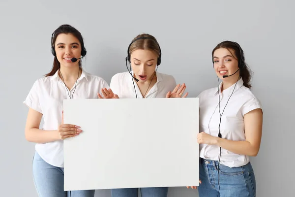 Female technical support agents with blank poster on light background