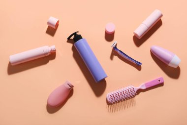 Renkli arka planda farklı kozmetik ürünler, saç fırçası ve güvenlik jileti
