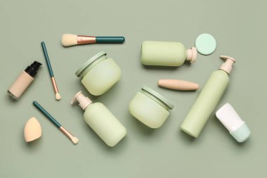 Renkli arka planda farklı kozmetik ürünleri, makyaj fırçaları ve süngerleri içeren kompozisyon