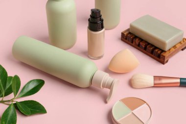 Pembe arka planda kozmetik ürünler ve makyaj aksesuarları