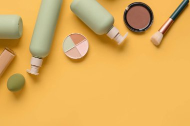 Sarı arka planda kozmetik ürünleri ve makyaj aksesuarlarıyla kompozisyon