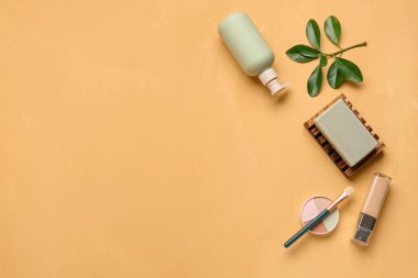 Renk arkaplanında makyaj fırçası olan kozmetik ürünleri