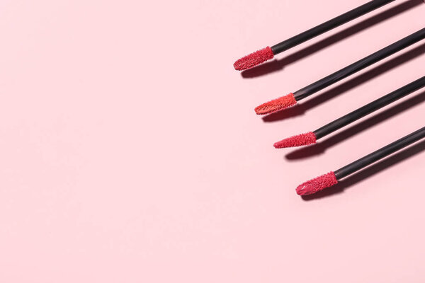 Different lipstick brushes on pink background