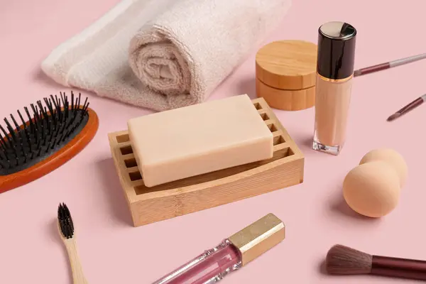Set of cosmetic products and bath supplies on pink background