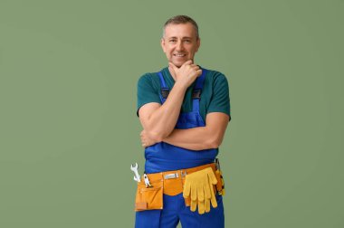 Yeşil arka planda alet kemeri olan erkek tamircinin portresi