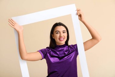 Bej arka planda çerçevesi olan güzel, mutlu genç bir kadın.