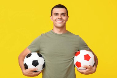 Sarı arka planda futbol topları olan yakışıklı genç adam.