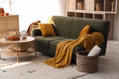 İçinde yeşil kanepe ve balkabağı olan oturma odasının içi.