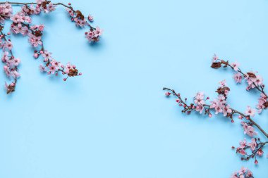 Mavi arkaplanda çiçek açan dallardan oluşan çerçeve