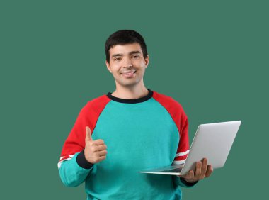 Yeşil arka planda dizüstü bilgisayarı olan erkek programcı