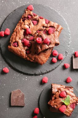 Üzerinde ahududulu çikolatalı kek ve siyah arkaplan parçaları olan tahtalar.