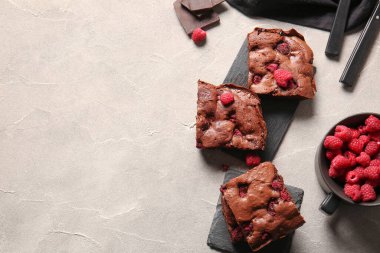 Gri masada ahududulu çikolatalı kek parçaları olan tahtalar.