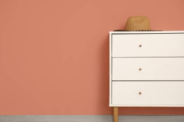 Renkli duvarın yanındaki çekmecelerin üstündeki hasır şapka