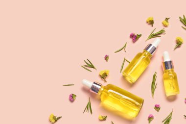 Soluk turuncu arka planda bitkilerle ve çiçeklerle dolu farklı sağlıklı yağlardan şişeler.