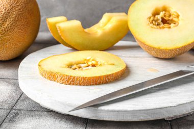 Gri fayansların üzerinde tatlı kavun parçaları olan tahta.