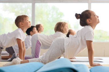 Beden dersinde yoga yapan bir grup çocuk.