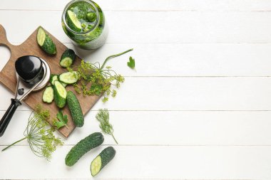 Taze salatalıklı kavanoz ve beyaz ahşap arka planda konserve konservesi malzemesi.