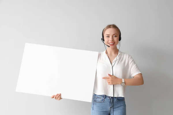 Female technical support agent with blank poster on light background