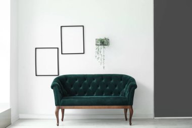 Beyaz duvarın yanındaki yeşil kanepe çok şık.