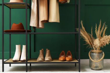 Salondaki yeşil duvarın yanında şapka ve ayakkabı askısı.