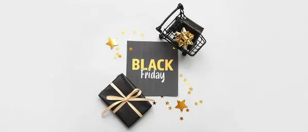 Card with text BLACK FRIDAY, gift boxes and shopping cart on white background
