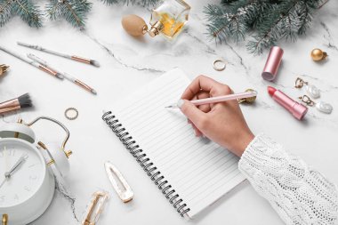 Not defterine Noel dekoru, aksesuarları ve çalar saati olan bir kadın grunge arkaplanda yazıyor.