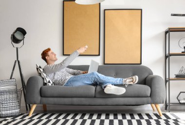 Bilgisayarlı genç adam evdeki klimayı açıyor.