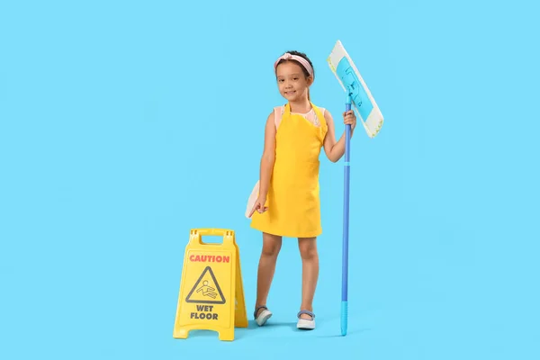Cute little janitor with mop and caution sign on blue background