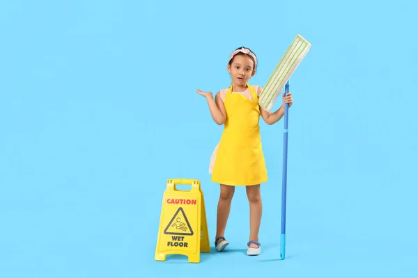 Cute little janitor with mop and caution sign on blue background