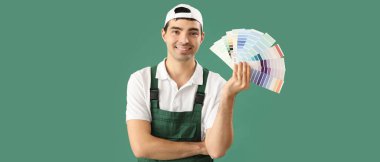 Yeşil arkaplanda renk paletleri tutan erkek dekoratör  