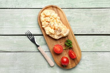 Çırpılmış yumurtalı sandviç ve domatesli yeşil ahşap arka plan.