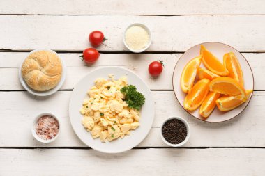 Lezzetli omlet tabağıyla kompozisyon ve beyaz ahşap arka planda malzemeler.