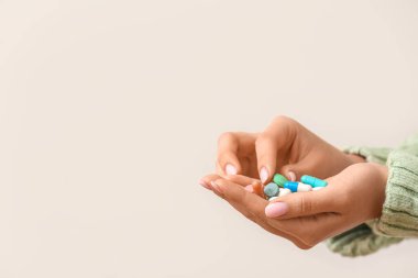 Beyaz arka planda farklı haplar tutan bir kadın.