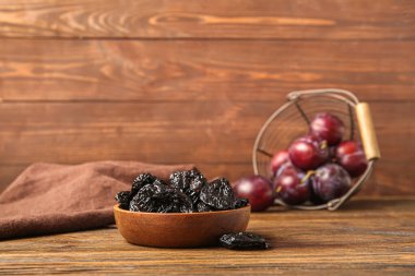 Lezzetli kuru eriklerle dolu bir kase ve ahşap masada olgun erikler