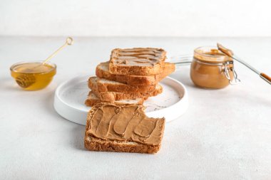Fıstık ezmeli tost tabağı ve beyaz arka planda bal.