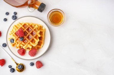 Böğürtlenli lezzetli waffle tabağı ve beyaz arka planda akçaağaç pekmezi.