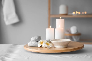 Kaplıca salonundaki kanepede taş ve çiçeklerle mum yakmak, yakın çekim.